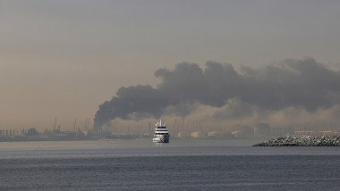 Un iaht navighează pe lângă un nor de fum care se ridică din portul Jebel Ali, în urma unui atac iranian raportat în Dubai, la 1 martie 2026
