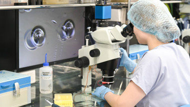 cercetator se uita prin microscop