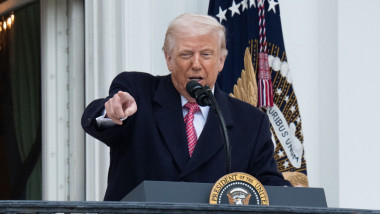 d trump la pupitru cu microfon, face gest cu mana