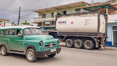 An old American car drives past a truck belonging to a private Cuban company (mipyme) parked in front of a gas station with an IsoTank of imported fuel in Havana on March 19, 2026