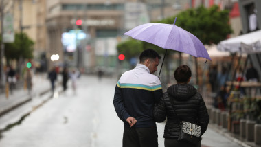 oameni cu o umbrela pe strada in bucurești