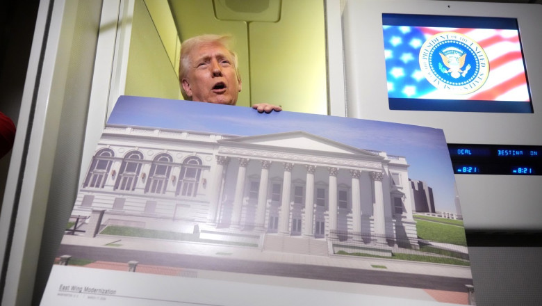 President Donald Trump holds a rendering of the proposed new East Wing of the White House as he speaks to reporters aboard Air Force One