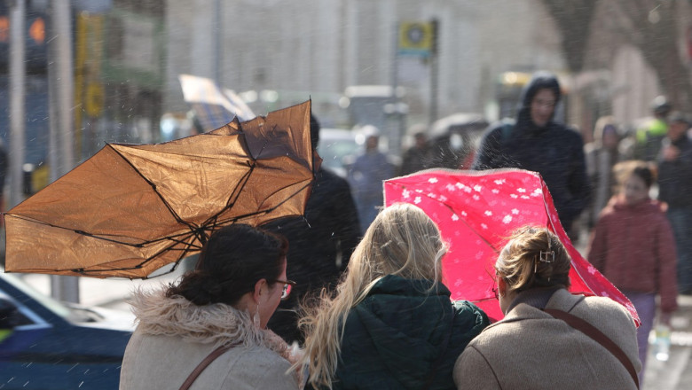 femei cu umbrele in vant pe strada