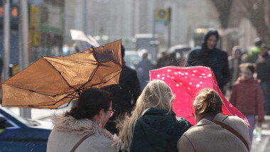 femei cu umbrele in vant pe strada