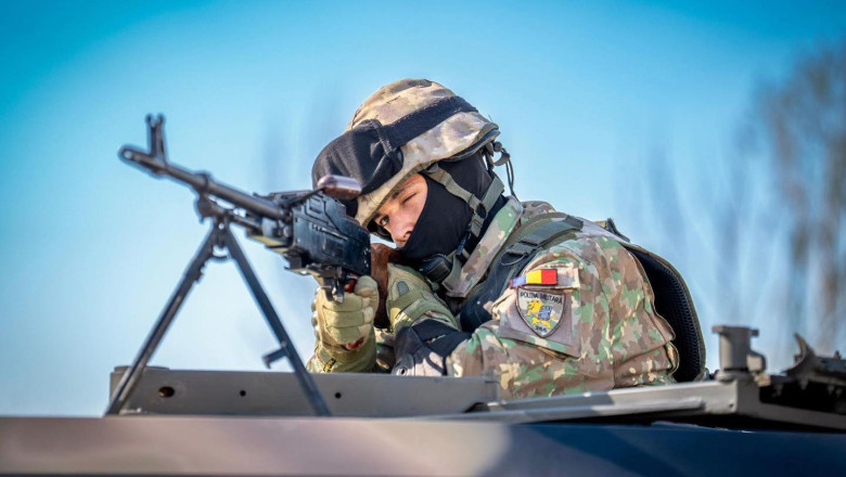 soldat roan in uniforma de camuflaj cu arma la ochi