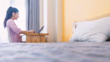 Blurred photo Woman working on a laptop from hotel. Workplace in a small apartment. Always in touch. Work from home concept.