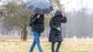 doi oameni cu o umbrela in ploaie