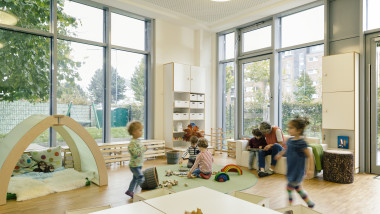 Pre-school teacher and children in playing in learning room in kindergarten