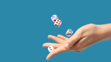 Female hand throwing game dices on blue background