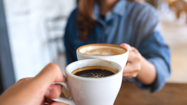 doua persoane cu cani de cafea
