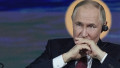 Vladimir Putin cu mainile la gura si casca in ureche