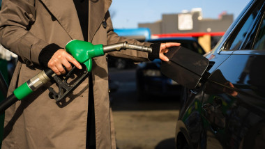 Fuel pump inserting into tank during refueling. Close-up of hand refilling vehicle with gasoline