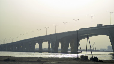 A long concrete bridge stretches across a calm river under a hazy sky. Abu Dhabi, UAE