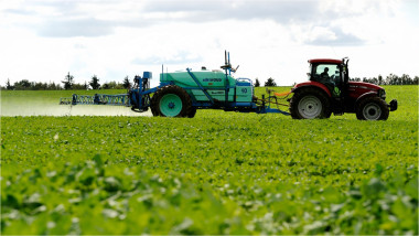 tractor împrăștie îngrășăminte pe un teren agricol