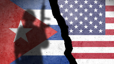 Flag of Cuba and USA painted on a concrete wall with soldier shadow