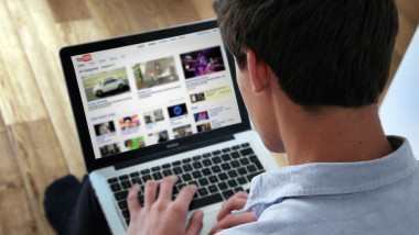 barbat care se uita la youtube pe laptop