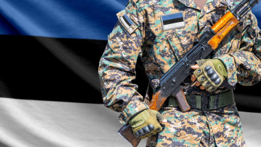 Estonia flag with soldier in military uniform holding assault rifle in front of it