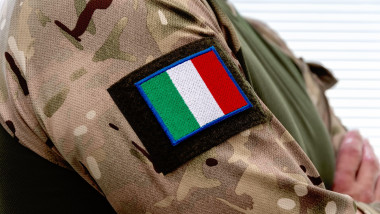 A man in an army uniform with an Italian flag on his sleeve and army badges