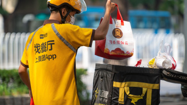 A Meituan courier picks up food from a restaurant and loads it on an electric scooter in Beijing, China. 13-Sep-2021