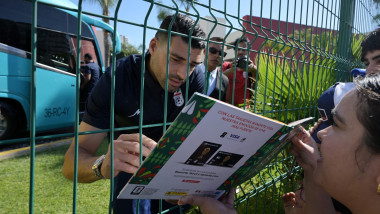 Iran's forward Mehdi Taremi signs autographs for a fan through the fence outside the Marriott Hotel before leaving for a training session in Tijuana