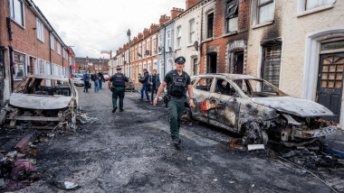 ofiteri de politie pe strada in belfast intre masini incendiate