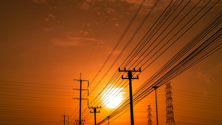 High voltage electric pole and transmission lines at sunset time with orange and red sky and clouds. Architecture. Silhouette electricity pylons durin
