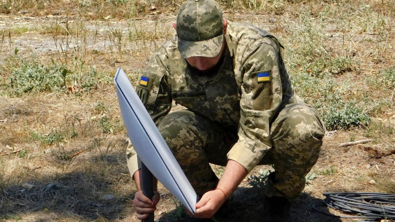 Un soldat ucrainean instalează o antenă Starlink pentru conexiune la internet prin satelit