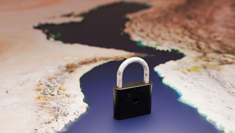 symbolic black padlock stands in the narrow Strait of Hormuz on a map of Iran. Conceptual image representing oil transit blockage, geopolitical tensio