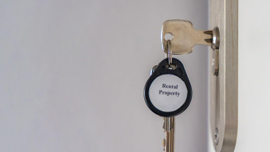 House keys with Rental Property keychain inserted into apartment door lock with copy space. Real estate rental and property management concept for