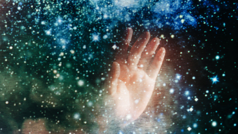 A human hand reaches into a glowing cosmic galaxy on a digital screen with visible scanlines.