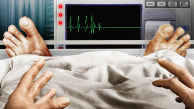 Frightened man in hospital bed seeing flatline pulse trace on monitor