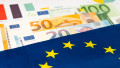 EU flag on euro banknotes with graph paper; business and finance concept.