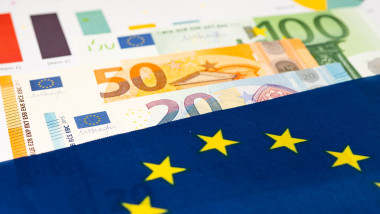 EU flag on euro banknotes with graph paper; business and finance concept.