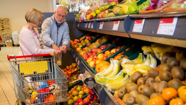 Older couple buys in a supermarket. Vegetables and fruits department.
