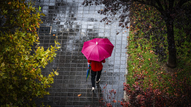o persoană cu o umbrelă roșie pe stradă