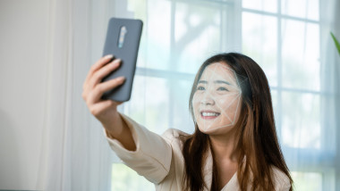 Asian women use smartphone for access control face recognition in private identification on sofa living room at home