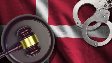 Denmark flag with judge mallet and handcuffs in dark room. Concept of criminal and punishment, background for judgement topics