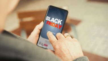 Black Friday sale promotion on smartphone screen with mature hands tapping. Online shopping, seasonal discounts, e-commerce promotions, mobile sales.