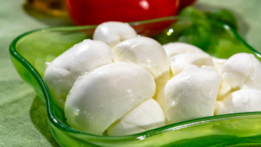 Twisted to form a plait treccia mozzarella Italian soft cheese served with fresh basil and tomatoes close up
