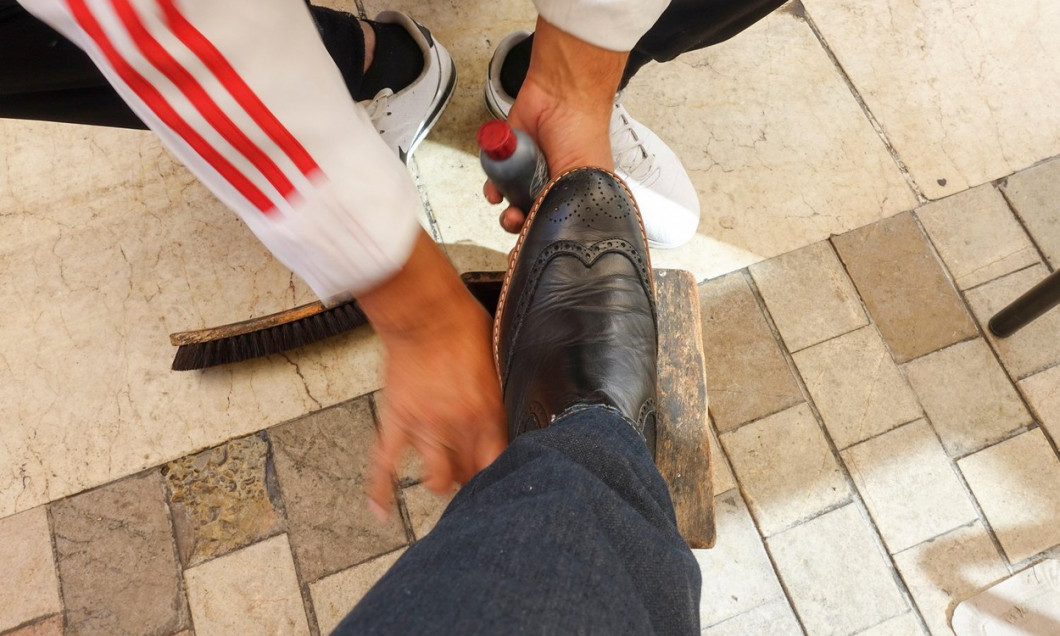 Shoe Shine Man, shoe cleaner, at work, Cleaning A Customer. Malaga, Andalusia, Spain.