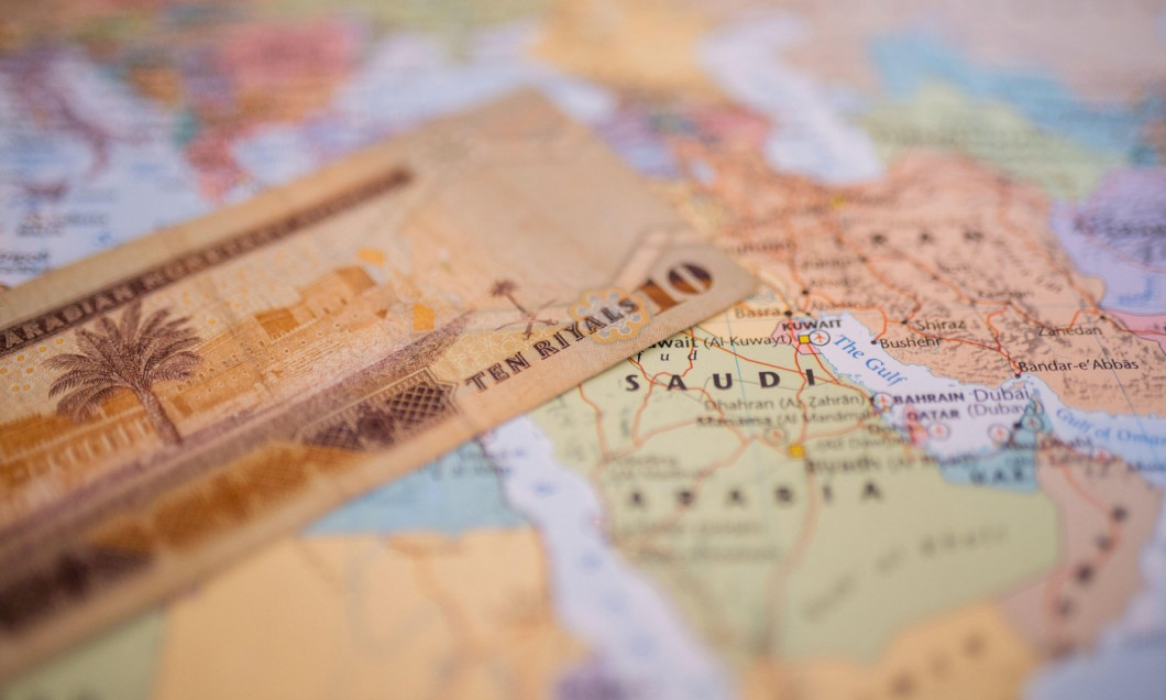 Ten riyals bill above Saudi Arabia on a colorful and blurry map of Western Asia
