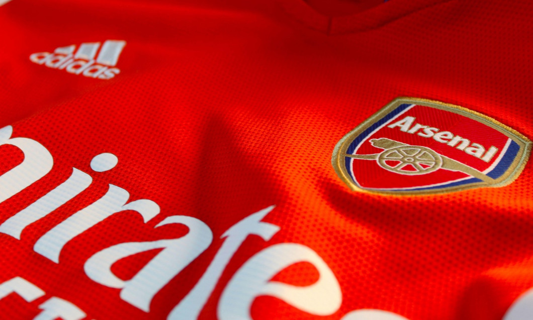 A photo of the red and white Arsenal Football Club t-shirt and badge.