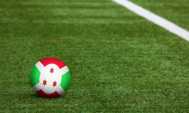 Burundi flag on ball at soccer field background. National football theme on green grass. Sports competition concept.