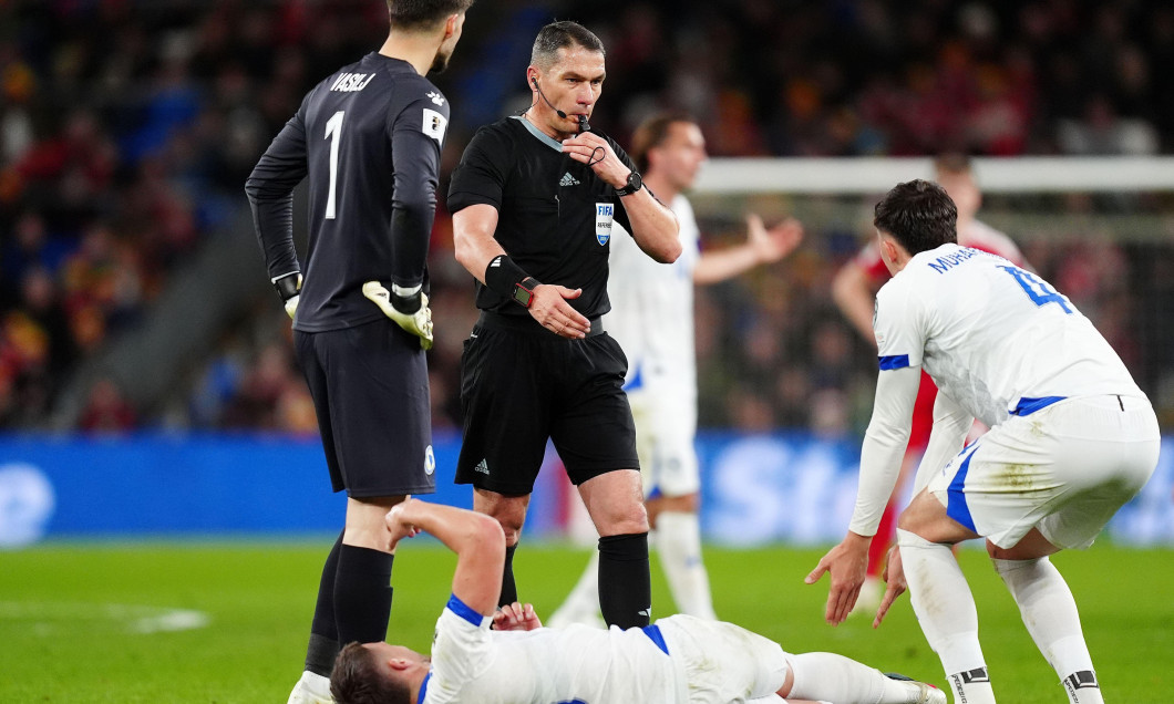 Referee Istvan Kovacs (centre) as Bosnia and Herzegovina's Ermedin Demirovic lays injured during the 2026 FIFA World Cup European Play-off Semi-final match at the Cardiff City Stadium. Picture date: Thursday March 26, 2026.