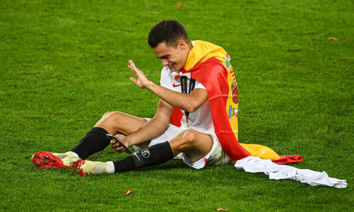 Cologne, Germany. 21st Aug, 2020. Football: Europa League, FC Sevilla - Inter Milan, Final-Eight, Final at the RheinEnergieStadion. Sevilla's Sergio Reguilon sits on the grass after the victory and greets someone via his smartphone. Credit: Federico Gamba