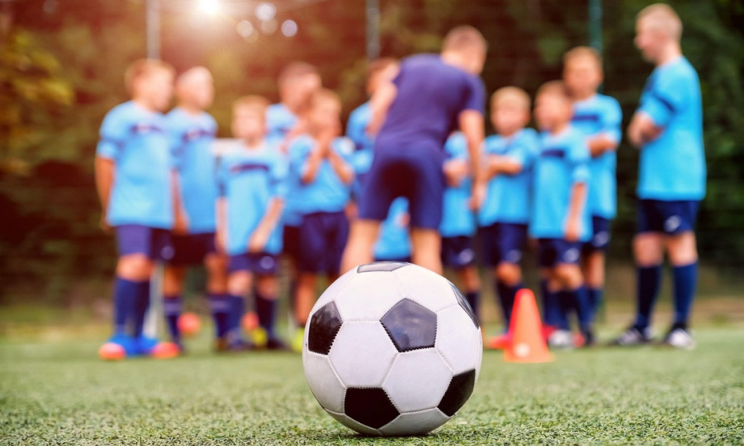 Soccer ball and blurred youth soccer team with coach on the field