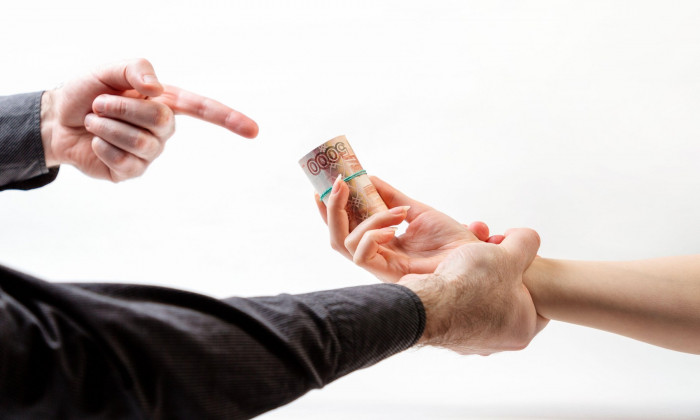 Bribery. A man's hand in a black shirt catches a woman's hand with a bribe. Side view. White background. The concept of the world anti-corruption day.