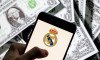 In this photo illustration Spanish professional football club team Real Madrid Club de Ftbol commonly known as Real Madrid logo seen on an Android mobile device screen with the currency of the United States dollar icon, $ icon symbol in the background.