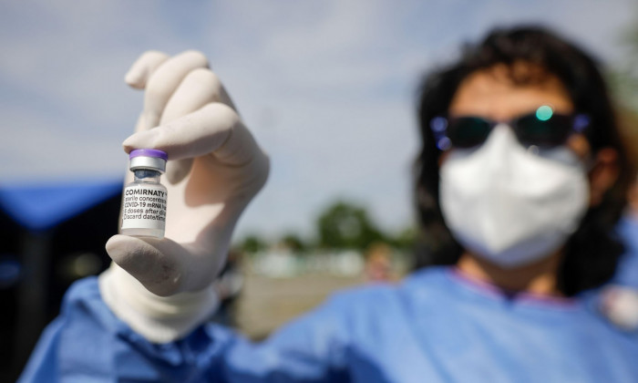 Bucharest, Romania - May 21, 2021: Details with the hand of a medical worker holding a dose of the Pfizer BioNTech Comirnaty anti Covid 19 vaccine at