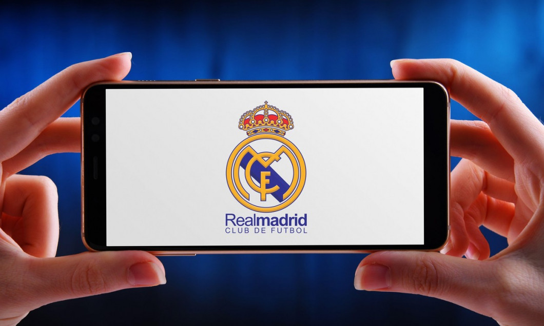 POZNAN, POL - JUN 20, 2020: Hands holding smartphone displaying logo of Real Madrid, a Spanish professional football club based in Madrid